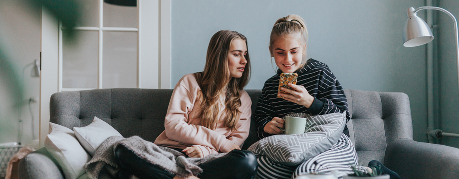 Venninner sitter i sofa og ser p mobil